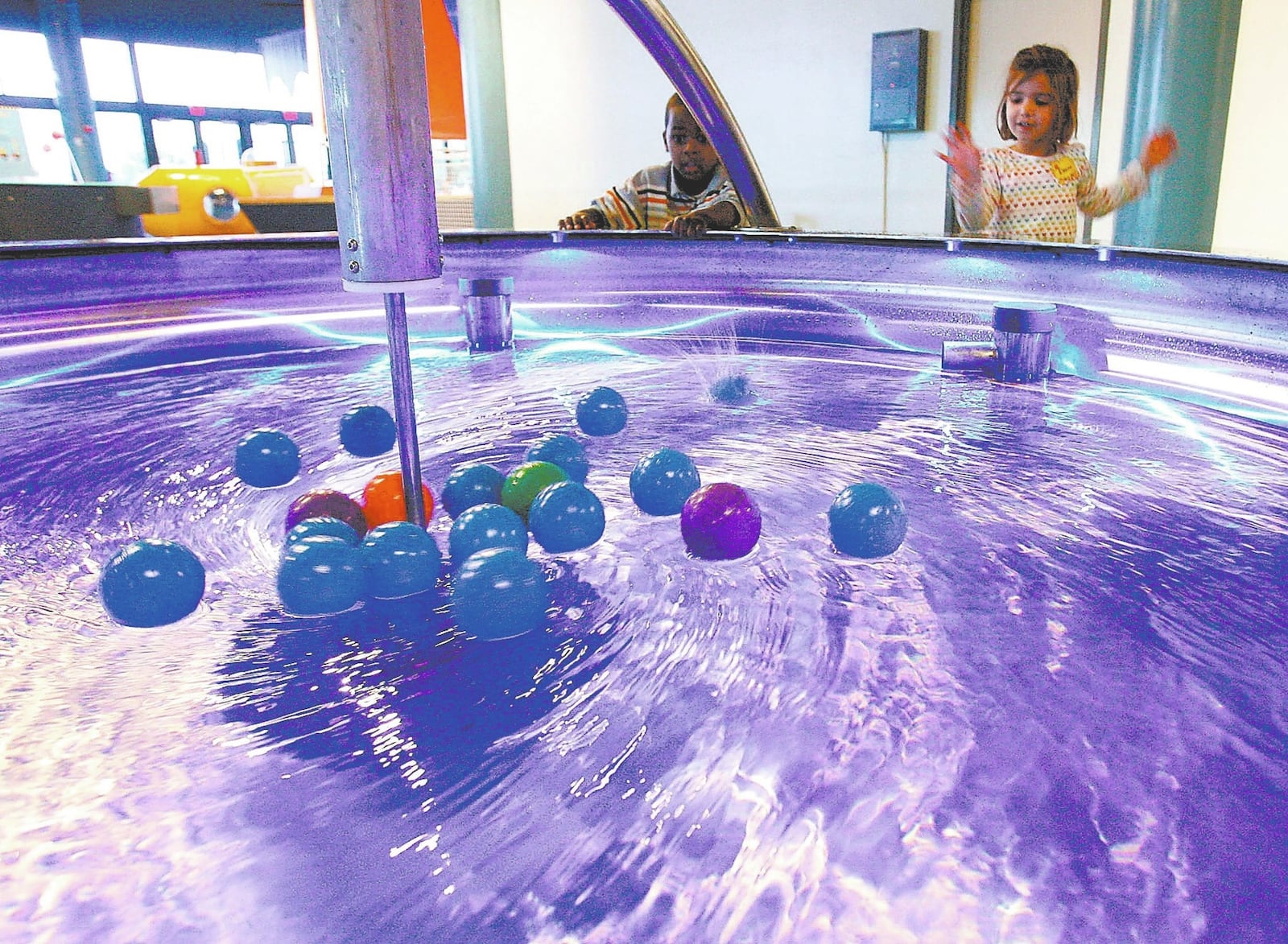 Musuem visitors watch balls move to the center of a swirling pool of water at the Imagination Station in Toledo. THE BLADE