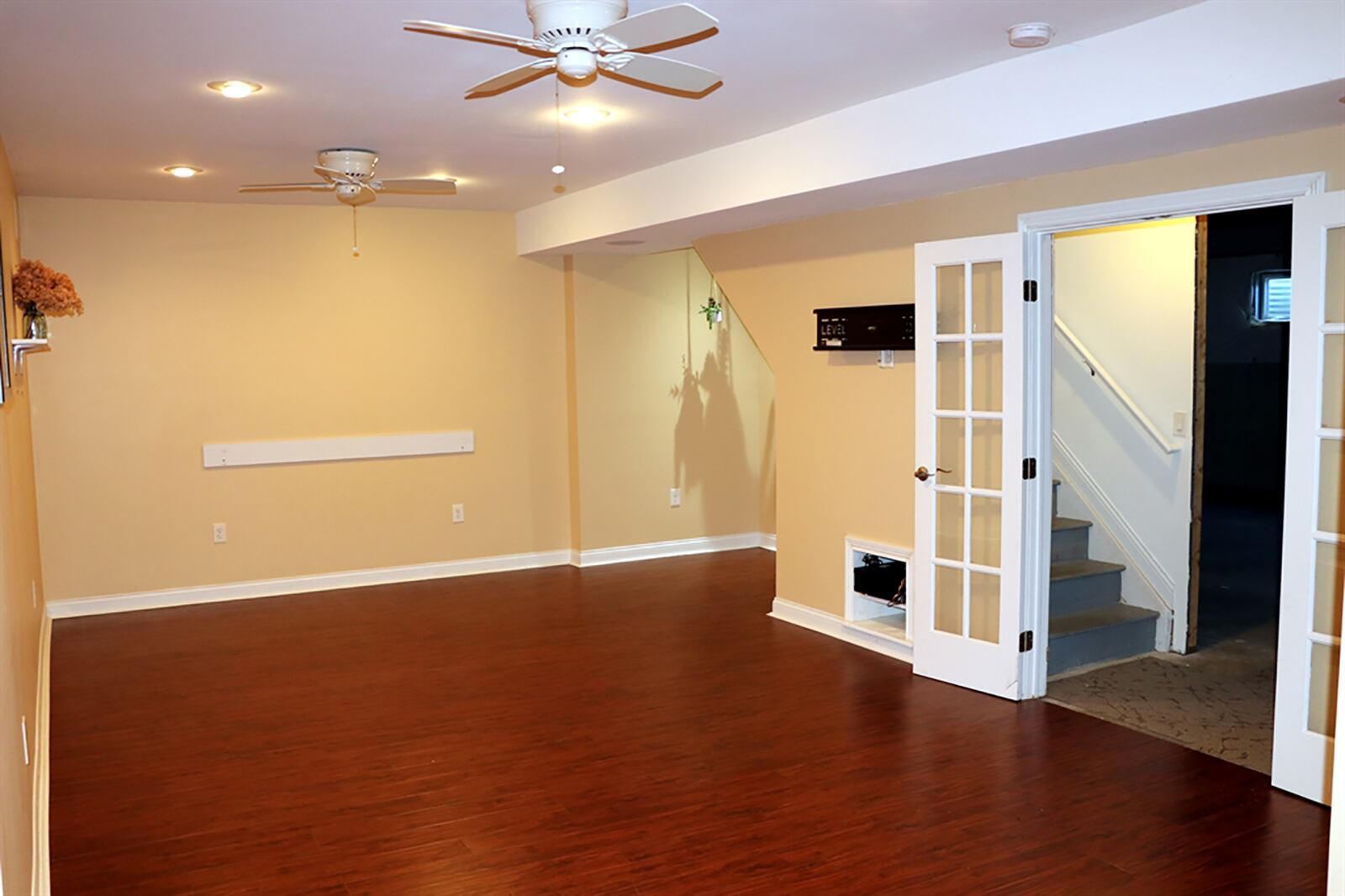 A door opens to a hidden staircase to the basement, which is mostly unfinished. Just off the staircase are French doors that open into a finished media room with manufactured wood-laminate flooring and ceiling paddle fans. The room has a spot for a wall-mount television and media equipment nook. CONTRIBUTED PHOTO BY KATHY TYLER