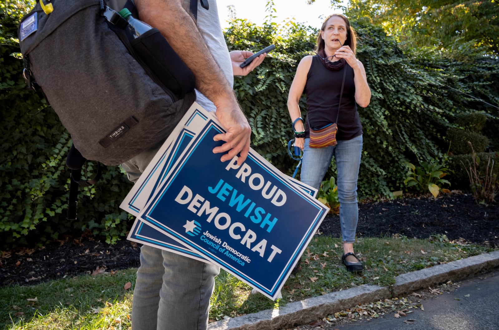 Dan Vogl, a doctor from Bala Cynwyd, left, talks to Chris Dorian as he goes door to door to canvass Jewish voters during the Jewish holiday of Sukkot in Bala Cynwyd, Pa., Sunday, Oct. 20, 2024. (AP Photo/Laurence Kesterson)