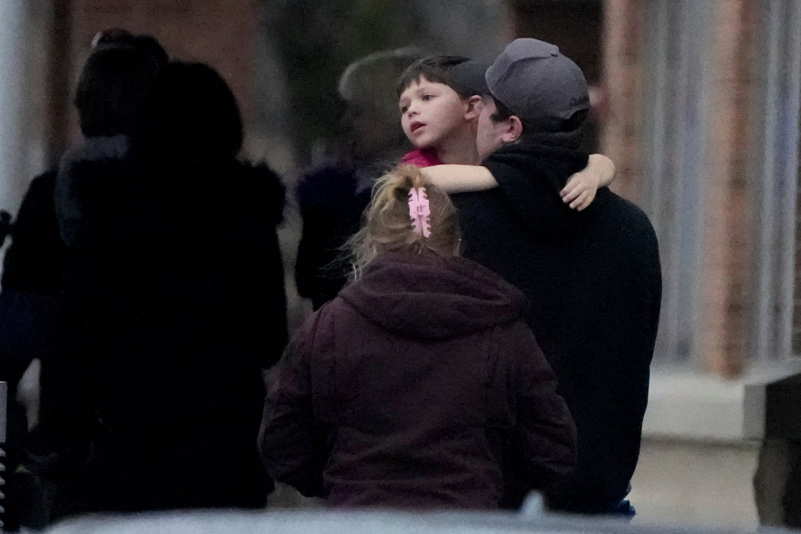 A child is embraced at the SSMI Health Center, set up as a reunification center, following a shooting, Monday, Dec. 16, 2024 in Madison, Wis. (AP Photo/Morry Gash)