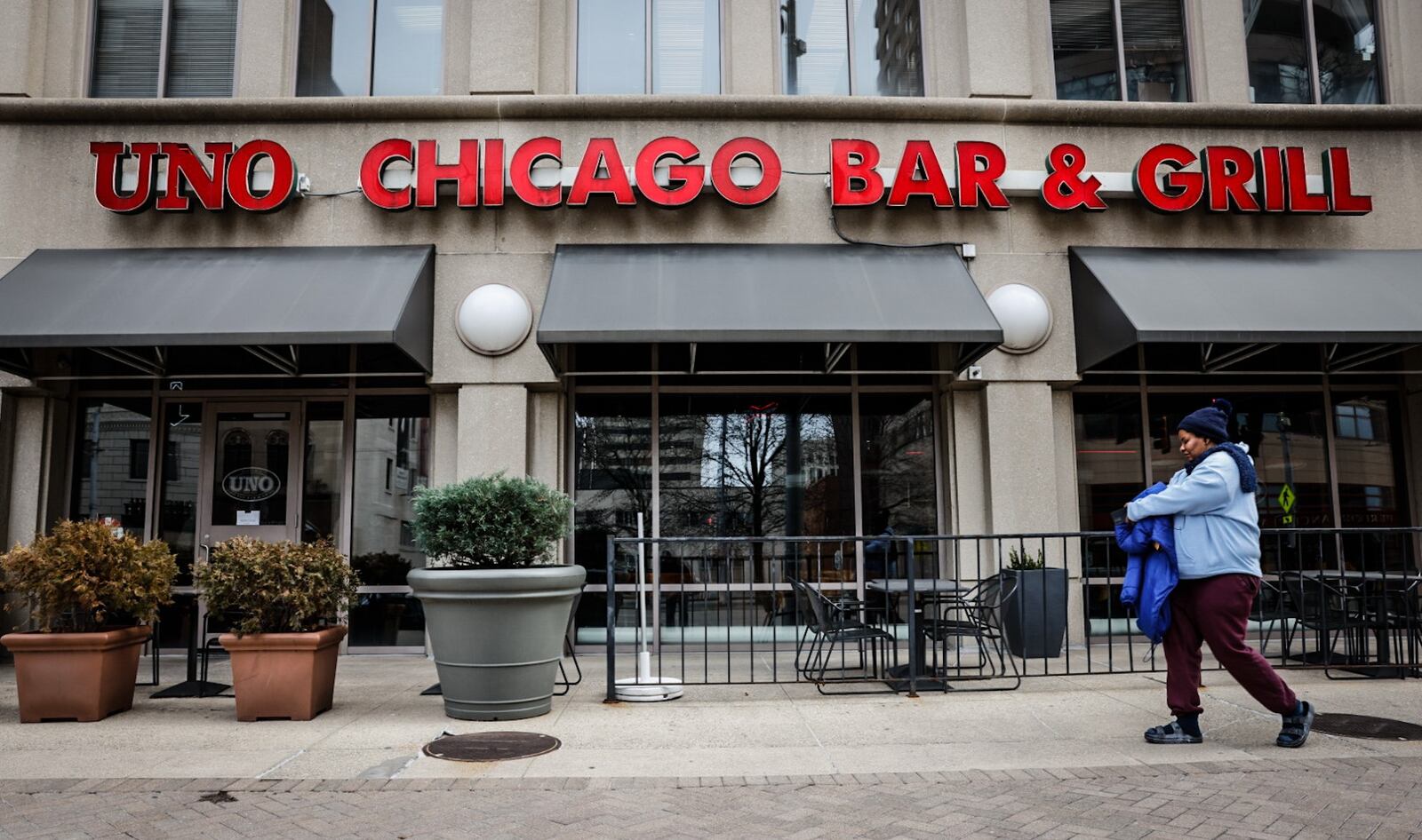 A pedestrian walks by Uno Chicago Bar & Grill Friday March 1, 2024. A sign on the door stated the pizzeria closed to the public February 29. JIM NOELKER/STAFF