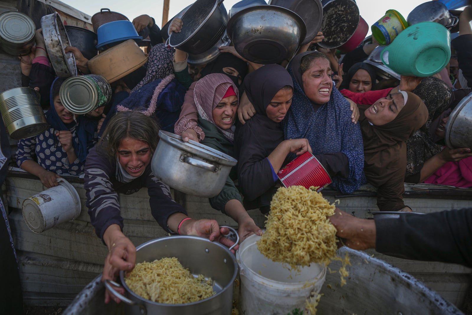 Palestinian girls struggle as they get donated food at a distribution center in Khan Younis, Gaza Strip, on Friday, Dec. 6, 2024. (AP Photo/Abdel Kareem Hana)