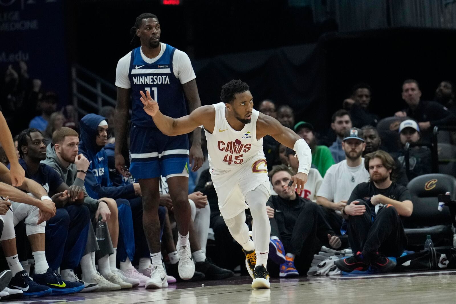 Cleveland Cavaliers guard Donovan Mitchell (45) gestures in front of Minnesota Timberwolves center Naz Reid (11) after hitting a 3-point basket in the first half of an NBA basketball game Monday, Feb. 10, 2025, in Cleveland. (AP Photo/Sue Ogrocki)