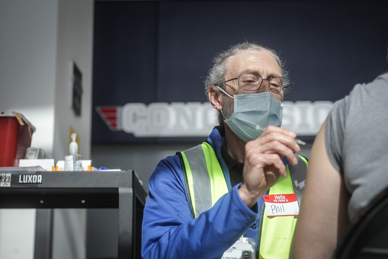 Premier Health R.N. Phil Frederick administers a COVID-19 vaccine at the University of Dayton Arena.