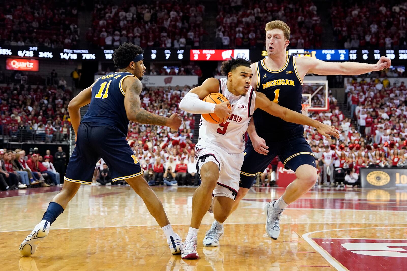 Wisconsin guard John Tonje (9) handles the ball against Michigan guard Roddy Gayle Jr. (11) and Michigan center Danny Wolf (1) during the second half of an NCAA college basketball game Tuesday, Dec. 3, 2024, in Madison, Wis. (AP Photo/Kayla Wolf)