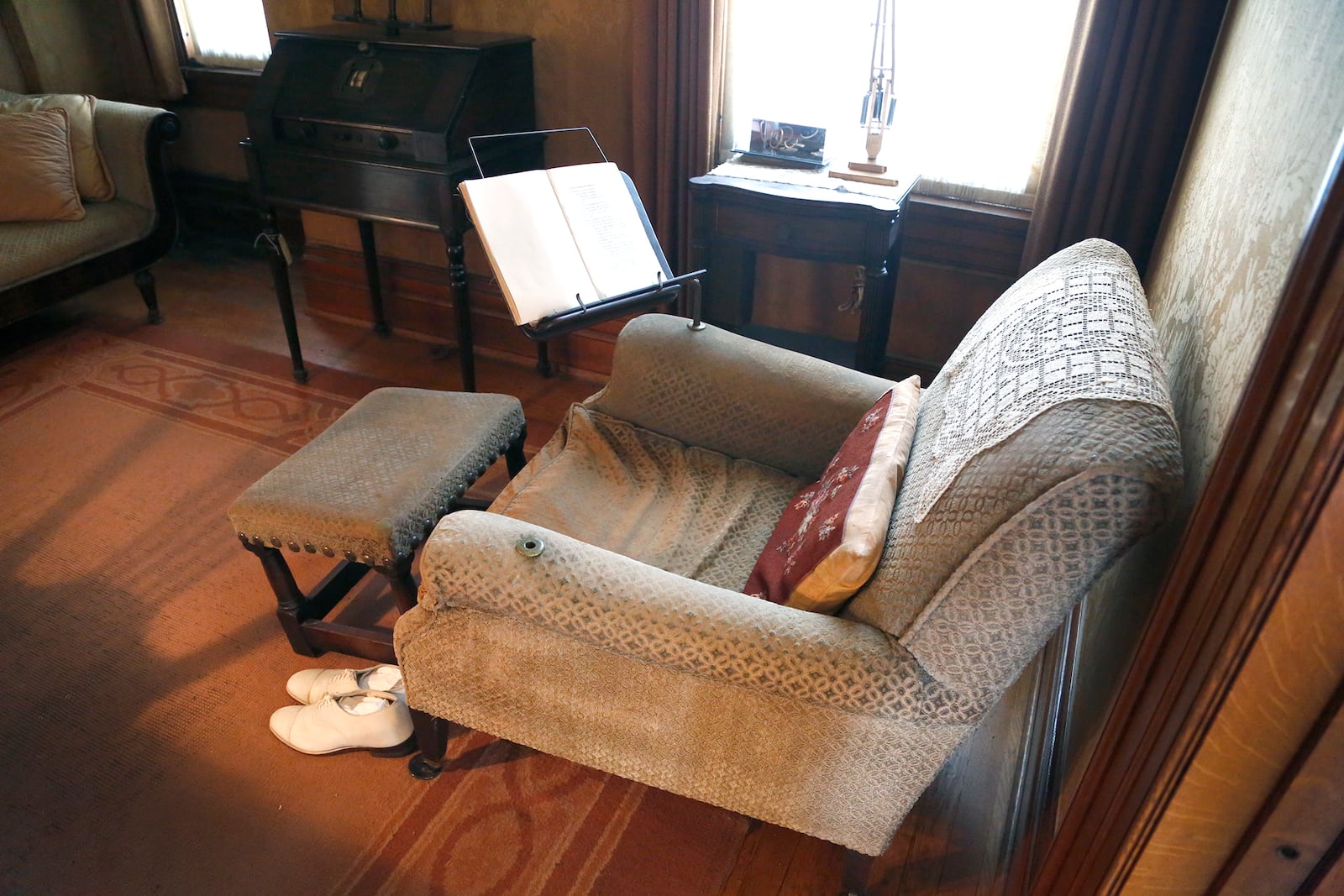 An arm chair Orville Wright modified to suit his needs sits by a window in the library. Wright, who suffered from back and leg pain caused by a 1908 crash, drilled a hole in each arm that a book stand could fit into to make reading more comfortable. He angled the footstool to take pressure off his legs. LISA POWELL / STAFF