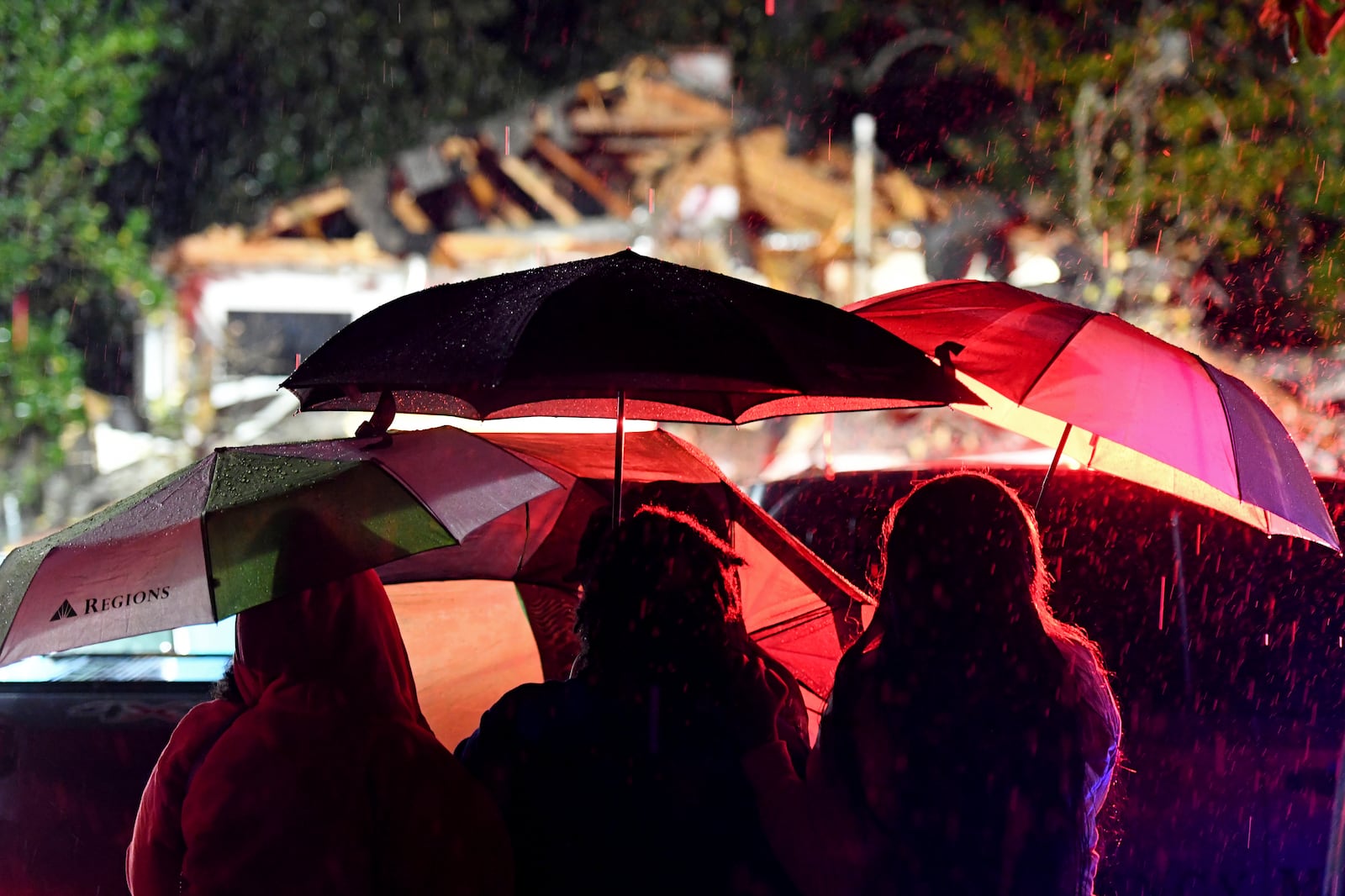 Bystanders watch as first responders work to free a victim after a tree fell on a house in Natchez, Miss., Saturday, Dec. 28, 2024. (Thomas Graning/The Natchez Democrat via AP)