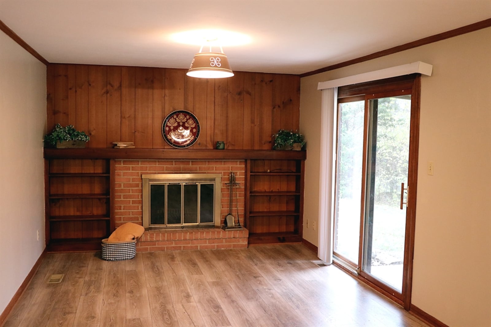 One wall of the family room has paneled walls with built-in bookcases that flank the brick fireplace.