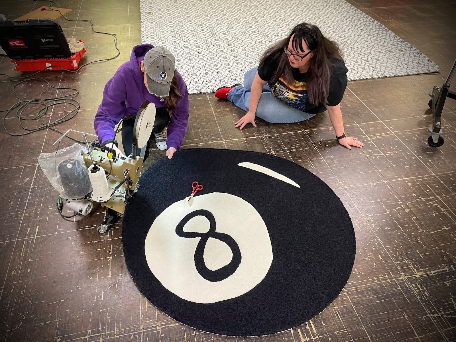 Rachel K. (right), who won this year’s rug design challenge, watches Rug Artisan Jessica Perrine (left) put the final touches on the rug she designed. NATALIE JONES/STAFF