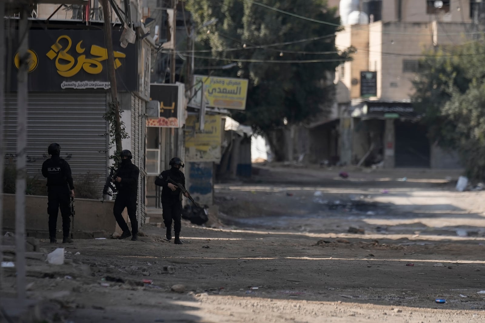 Officers from the Palestinian Authority clutch their guns as Palestinian security forces mount a major raid against militants in the Jenin refugee camp in the Israeli-occupied West Bank, Monday, Dec. 23, 2024. (AP Photo/Majdi Mohammed)