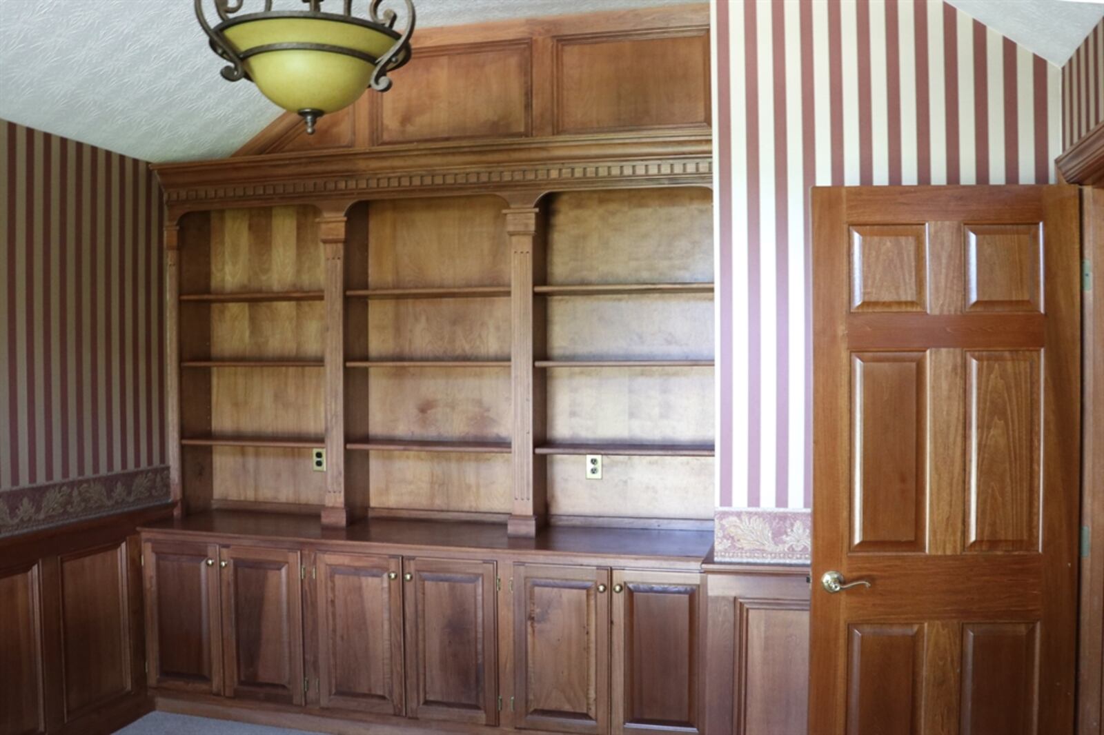 The study features a built-in bookcase with cabinets and wainscoting wraps around the room.