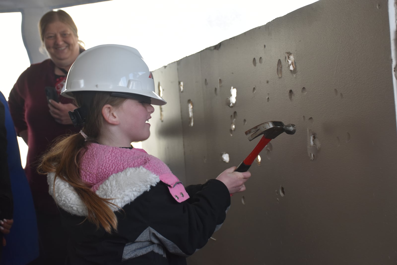 Elliana Mooney, 6, whacks a piece of drywall at East End Community Services' "wall breaking" event on April 4, 2024. Mooney lives in East Dayton. CORNELIUS FROLIK / STAFF