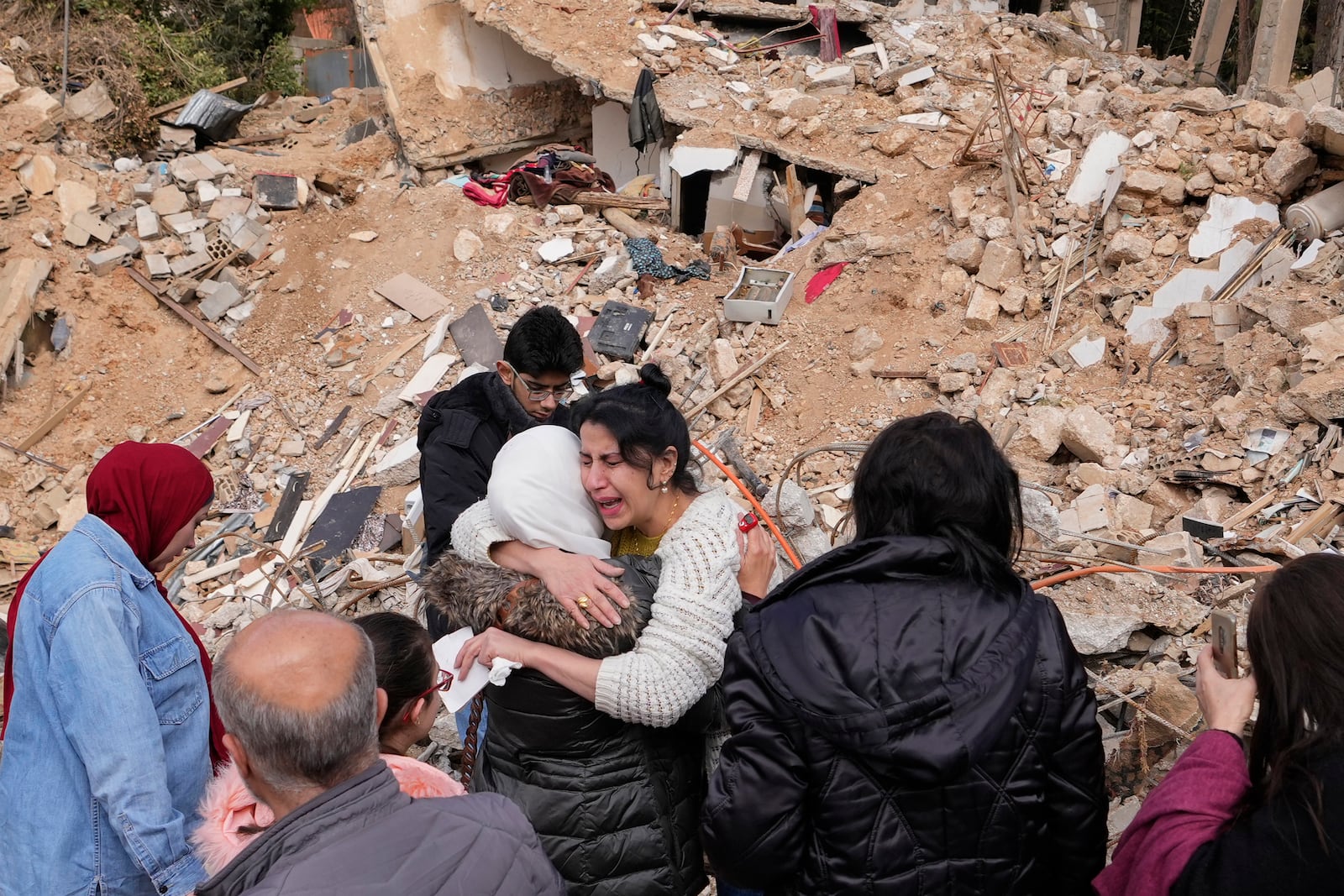 Displaced residents hug as they stand in front of the rubble of their destroyed house in Baalbek, eastern Lebanon, Thursday, Nov. 28, 2024. (AP Photo/Hassan Ammar)