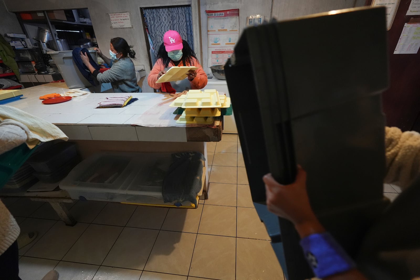 Margelis Rodriguez, of Venezuela, center, cleans up after dinner at the migrant shelter where she lives with her two children in Tijuana, Mexico, Friday, Jan. 31, 2025. (AP Photo/Gregory Bull)