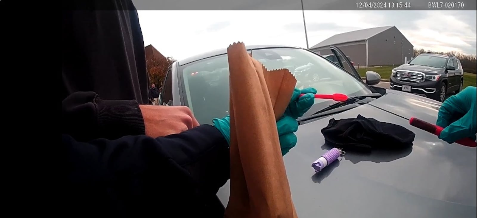 A screenshot of body camera video from a Huber Heights police officer shows an officer collecting what appears to be a filet knife and sheath as evidence in the Wednesday, Dec. 4, 2024, stabbing of a 16-year-old girl at Community Park.