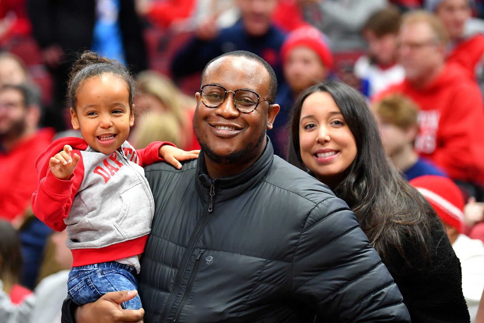 Rick Roshto's 2 1/2 year old granddaughter Vivienne in her Dayton Flyers hoodie at UD's game versus Wyoming at the United Center in Chicago on Dec. 17. She's pictured with her parents, Jude and Lisa Odafe, both UD grads. Lisa is Rick's daughter. CONTRIBUTED