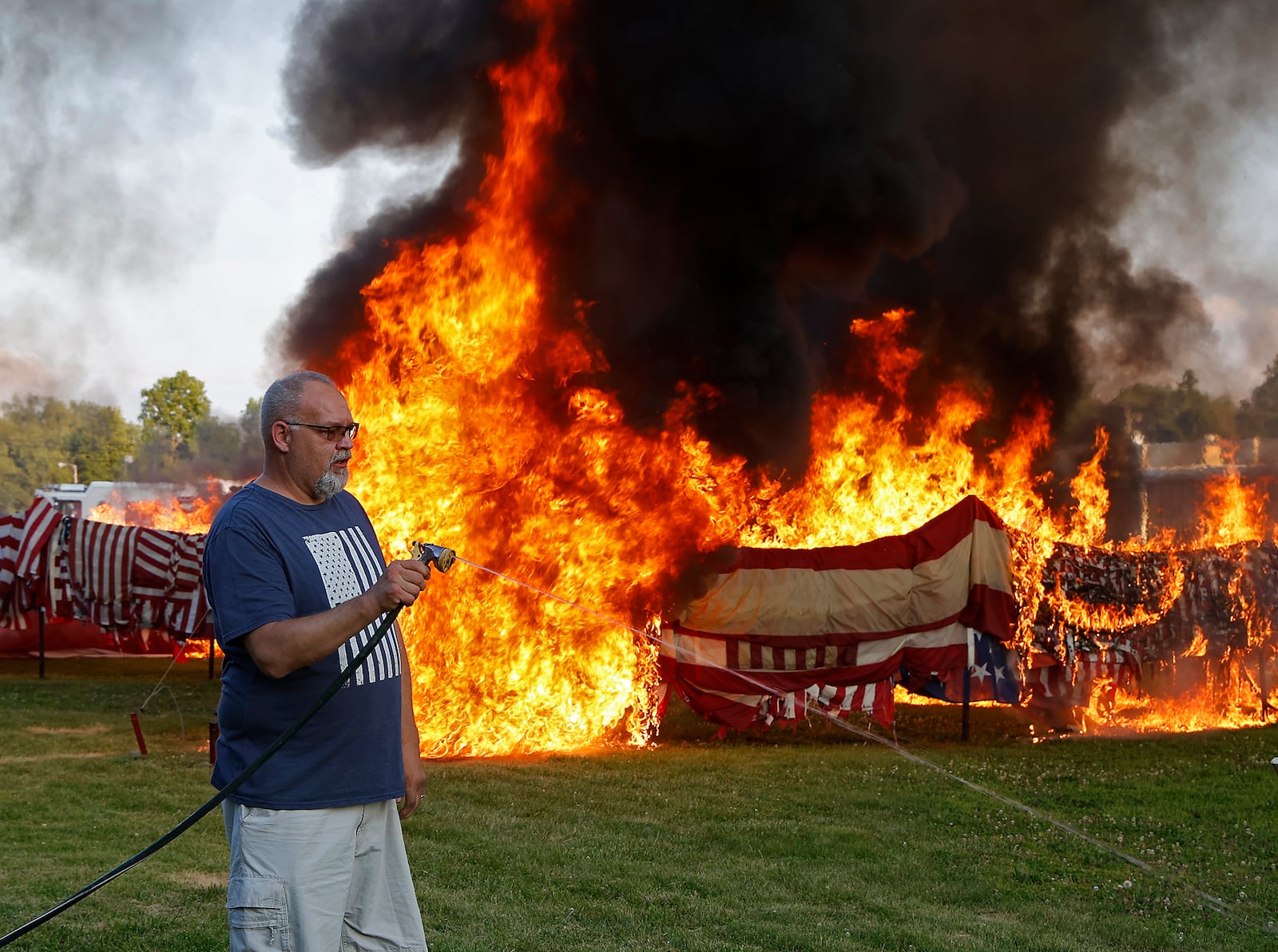 Tony Rieker extinguishes the torches after helping light thousands of American flags during the annual flag retirement ceremony at American Legion Post 286 in New Carlisle Friday, June 14, 2024. The American Legiion receives thousands of faded and worn out flags from all over the country to officially retire. This year they retired between 8,000 an 10,000 flags. BILL LACKEY/STAFF