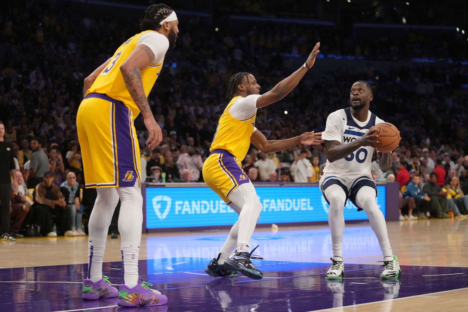 Minnesota Timberwolves forward Julius Randle (30) works toward the basket as Los Angeles Lakers guard Bronny James, center, and forward Anthony Davis defend during the first half of an NBA basketball game, Tuesday, Oct. 22, 2024, in Los Angeles. (AP Photo/Eric Thayer)