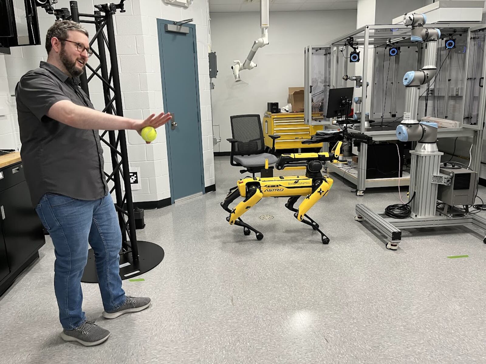 Sean Donegan, research lead for digital manufacturing at the Air Force Research Lab at Wright-Patterson Air Force Base, prepares to play fetch with a Boston Dynamics robotic dog at AFRL's new Collaborative Automation for Manufacturing Systems (CAMS) Laboratory. THOMAS GNAU/STAFF