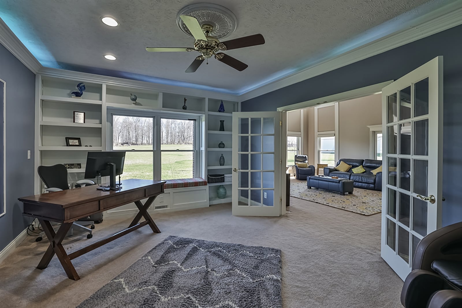 Oversized French doors open into a study with lower crown molding that hides accent lighting and blends into the built-in bookcases that surrounds double windows which also have a built-in window seat with storage. CONTRIBUTED PHOTO