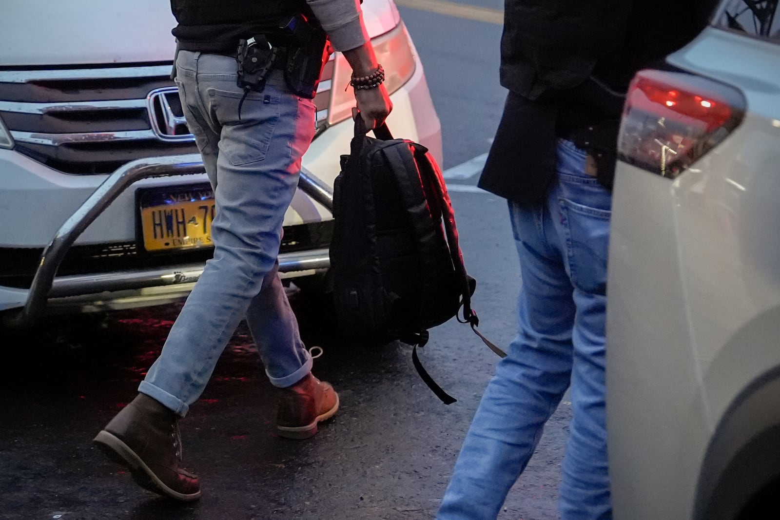 A deportation officer with Enforcement and Removal Operations in U.S. Immigration and Customs Enforcement's New York City field office carries the backpack of Wilmer Patricio Medina-Medina after arresting him during an early morning operation, Tuesday, Dec. 17, 2024, in the Bronx borough of New York. (AP Photo/Julia Demaree Nikhinson)