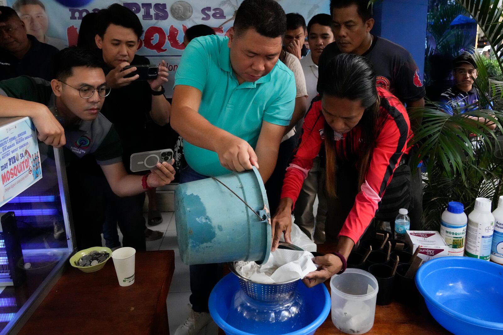 Village chief Carlito Cernal, center, pours a container with mosquito larvas that was captured by a resident in Mandaluyong city, Philippines as their village started offering bounty for captured mosquitos, dead or alive, as part of an anti-dengue campaign on Wednesday, Feb. 19, 2025. (AP Photo/Aaron Favila)