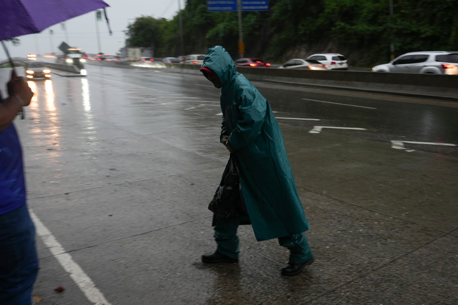 A man walks to his work place during rains brought on by tropical storm Sara in San Pedro Sula, Honduras, Friday, Nov. 15, 2024. (AP Photo/Moises Castillo)