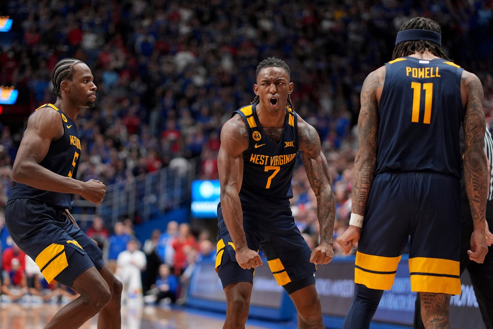 West Virginia guard Javon Small (7) celebrates with teammates after making a basket during the second half of an NCAA college basketball game against Kansas, Tuesday, Dec. 31, 2024, in Lawrence, Kan. West Virginia won 62-61(AP Photo/Charlie Riedel)