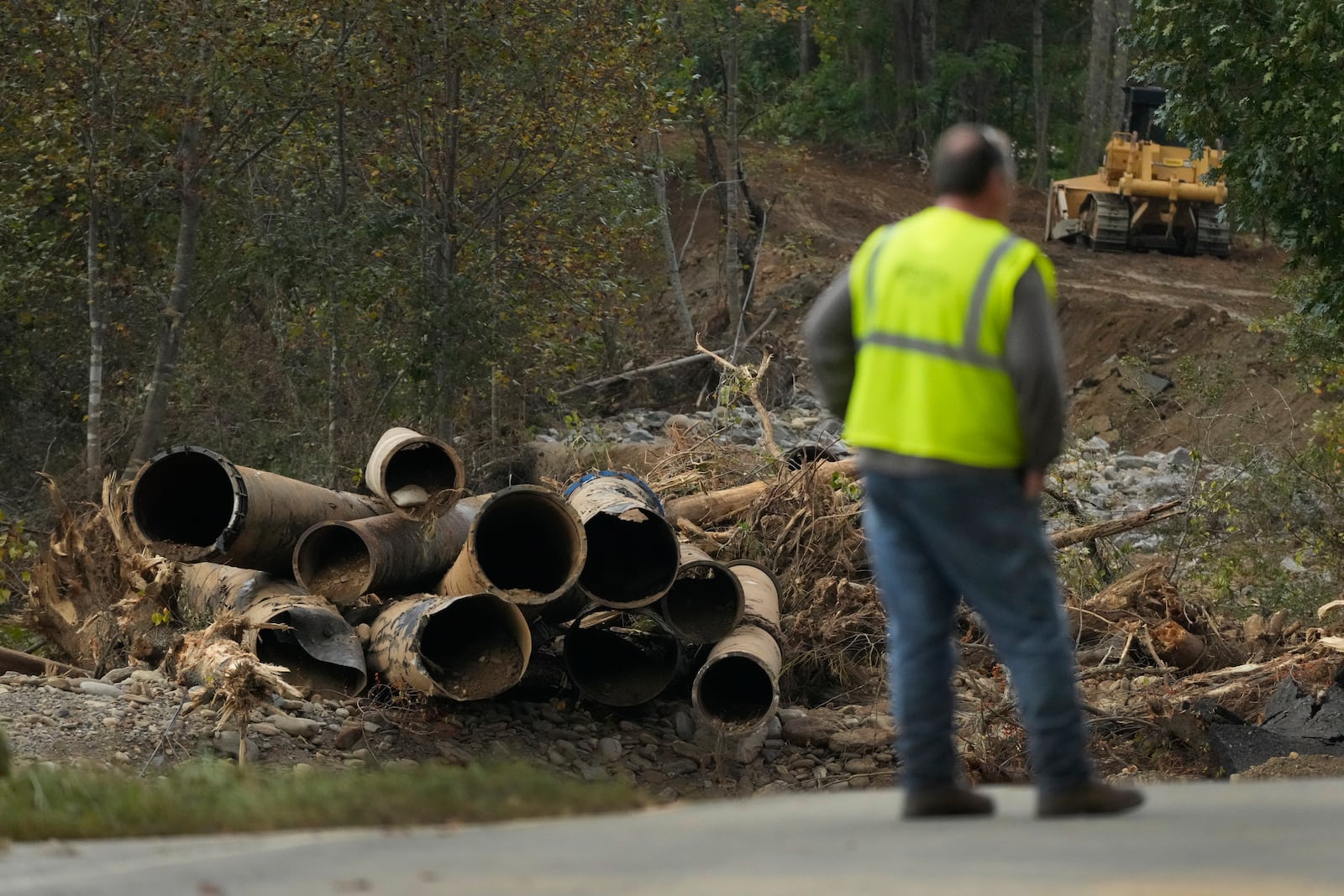 Electrical contract worker Matthew Tipton looks over the remnants of a waterline serving Asheville, N.C., downstream from North Fork Reservoir, a main source of water for the city, Wednesday, Oct. 2, 2024, after the line was destroyed during Hurricane Helene in Black Mountain, N.C. (AP Photo/Jeff Roberson)