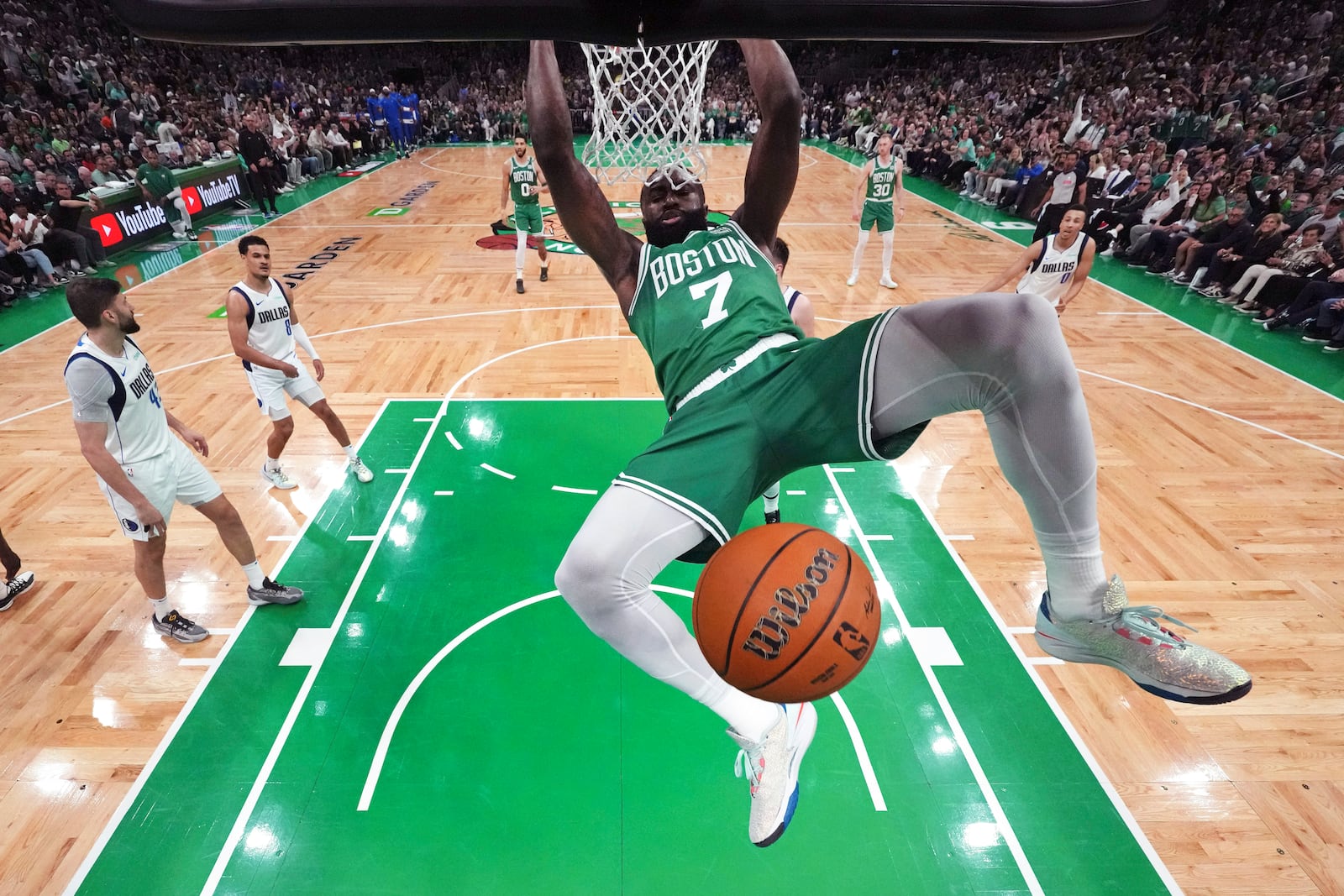 FILE - Boston Celtics guard Jaylen Brown (7) hangs on the rim after a dunk during the first half against the Dallas Mavericks in Game 5 of the NBA basketball finals Monday, June 17, 2024, in Boston. (Peter Casey/Pool Photo via AP, File)