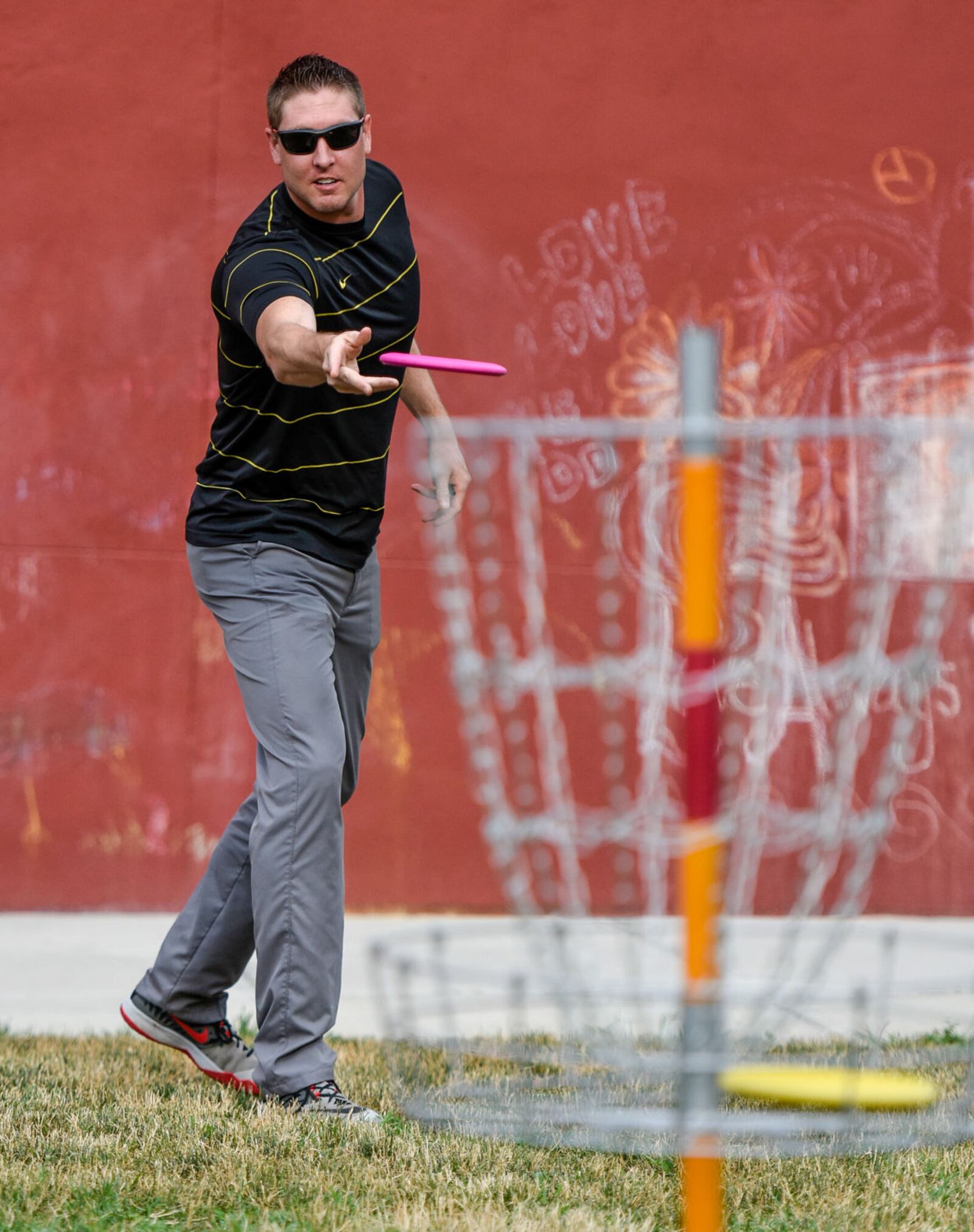 David Stark throws a disc golf disc at the basket at a display set up by the Hamilton Parks Conservancy to promote their 9-hole disc golf course at Millikin Woods Park during the Heroes version of Alive After 5 Thursday, July 7 in downtown Hamilton. They are also selling discs with Milliken Mile logo to help raise funds for improvements to the course. NICK GRAHAM/STAFF