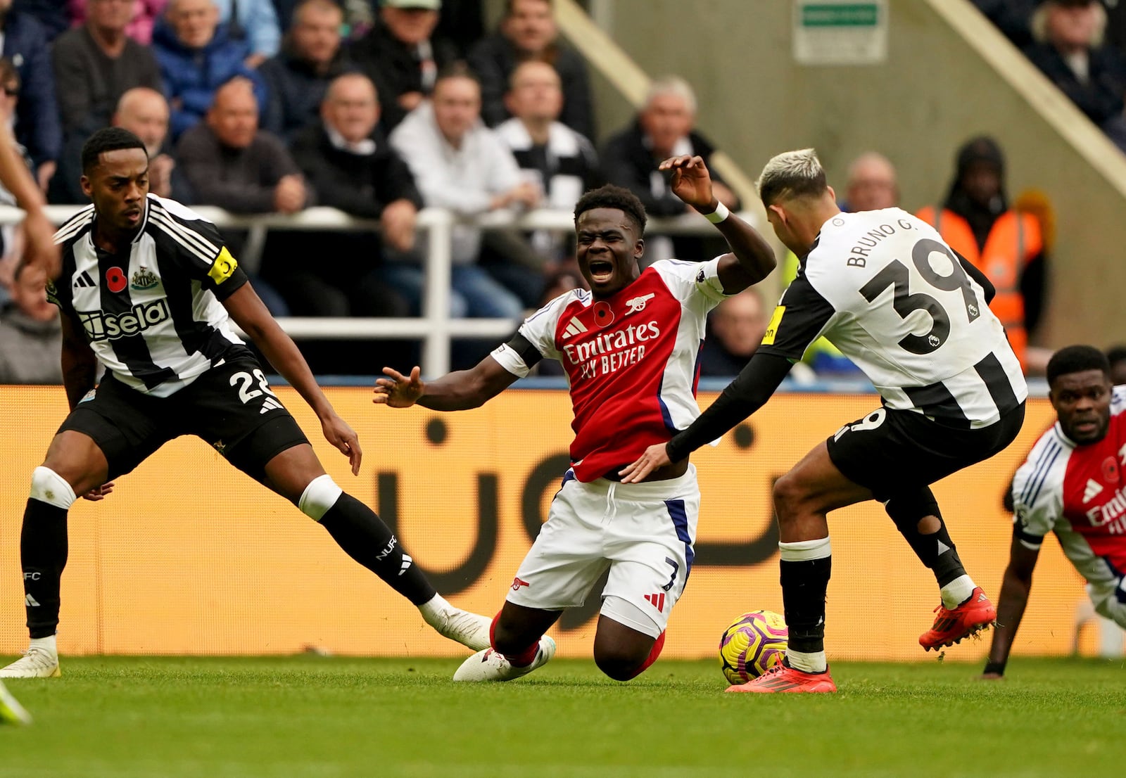 Arsenal's Bukayo Saka, center, is fouled by Newcastle United's Joe Willock, left, during the English Premier League soccer match between Newcastle United and Arsenal, at St James' Park, in Newcastle, England, Saturday, Nov. 2, 2024. (Owen Humphreys/PA via AP)