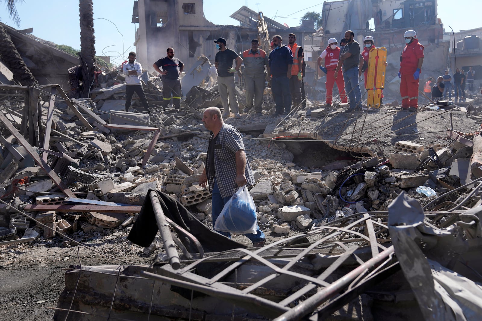 A man carries his belonging as he leaves the site of Israeli airstrikes that destroyed buildings facing the city's main government hospital in a densely-populated neighborhood, in southern Beirut, Lebanon, Tuesday, Oct. 22, 2024.(AP Photo/Hussein Malla)