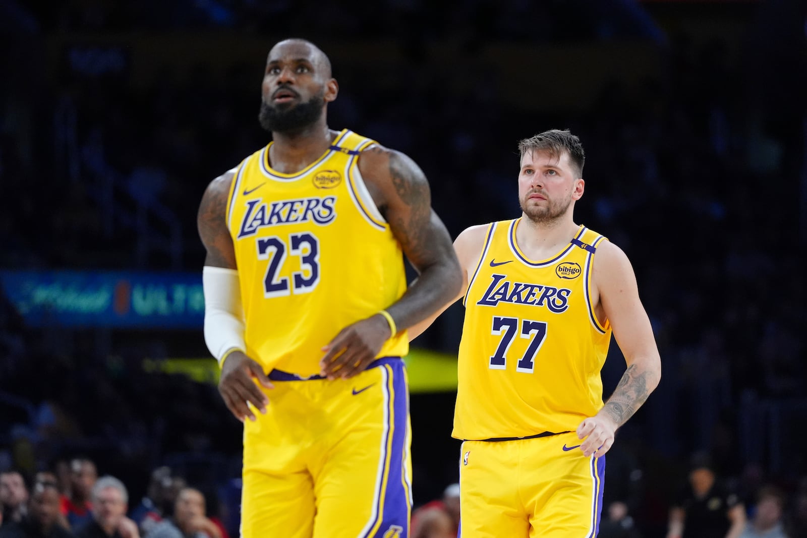 Los Angeles Lakers' LeBron James (23) and Luka Doncic (77) watch action during the second half of an NBA basketball game against the New Orleans Pelicans Tuesday, March 4, 2025, in Los Angeles. (AP Photo/Jae C. Hong)