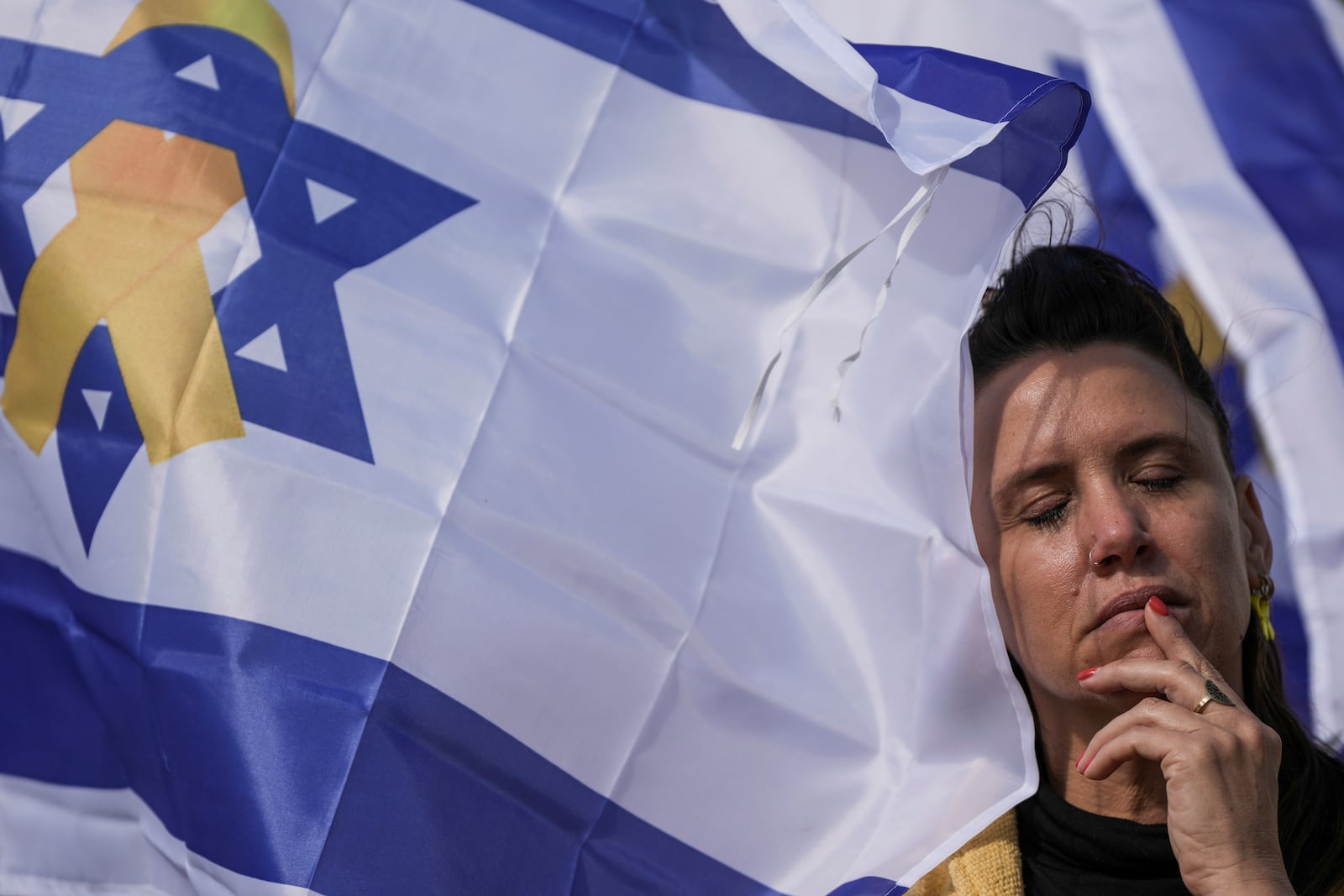 A woman reacts at the so-called 'Hostages Square' in Tel Aviv, Israel, Thursday, Feb. 20, 2025, as the bodies of four Israeli hostages, including a mother and her two children, are handed over by Hamas to the Red Cross in Gaza. (AP Photo/Oded Balilty)