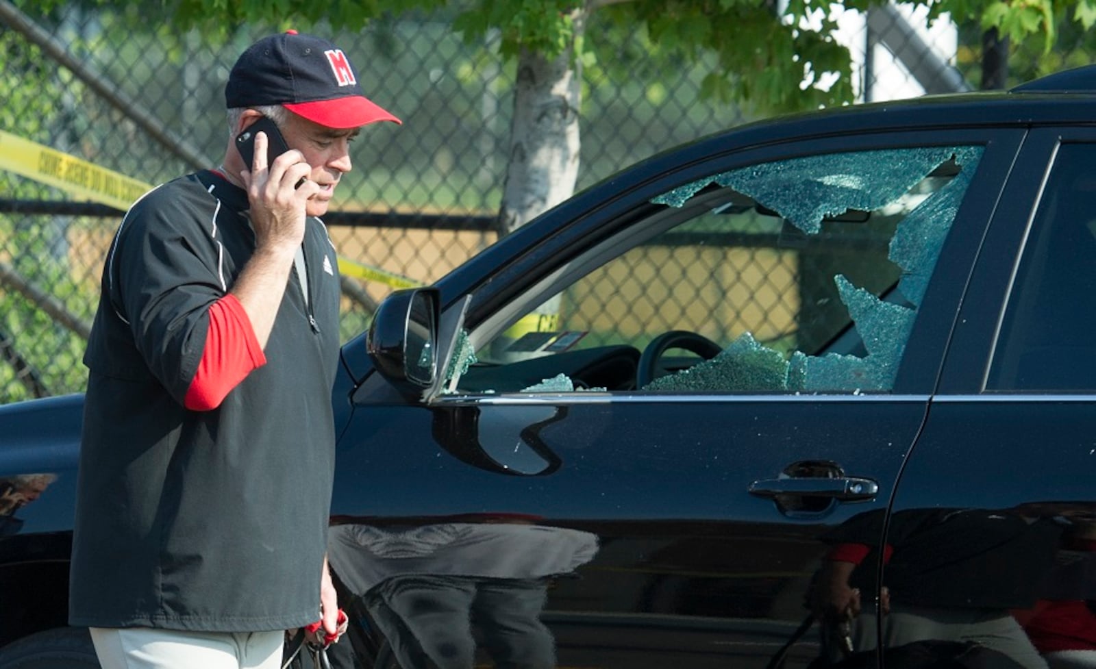 Rep. Brad Wenstrup, R-Ohio talks on the phone as he walks past a damaged vehicle in Alexandria, Va., Wednesday, June 14, 2017, after a shooting where House Majority Whip Steve Scalise of La., and others, were shot during a Congressional baseball practice. (AP Photo/Cliff Owen)