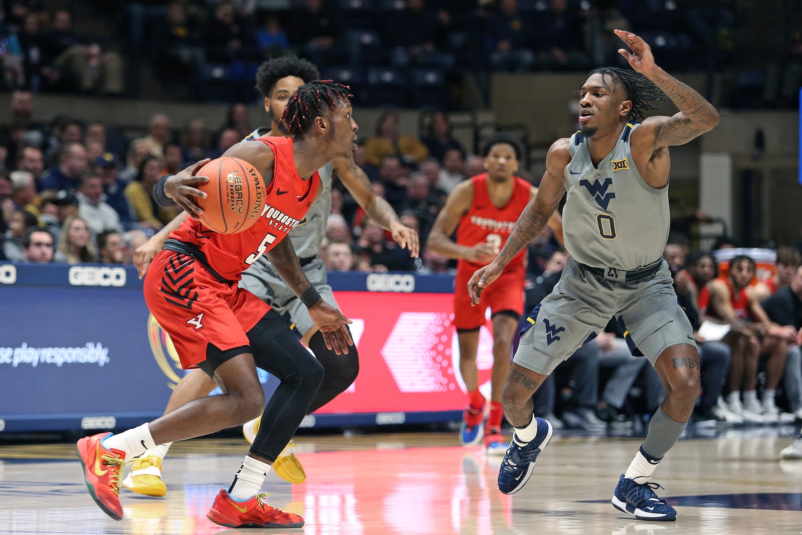 Youngstown State guard Dwayne Cohill (5) is defended by West Virginia guard Kedrian Johnson (0) and another player during the second half of an NCAA college basketball game in Morgantown, W.Va., Wednesday, Dec. 22, 2021. (AP Photo/Kathleen Batten)