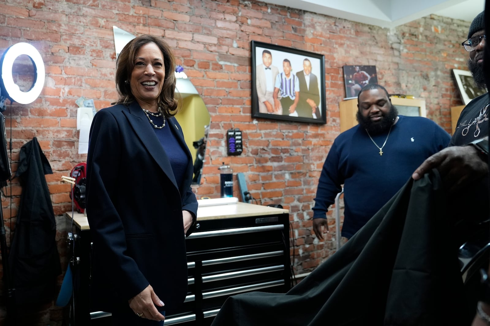 Democratic presidential nominee Vice President Kamala Harris, left, walks to sit in the "lucky chair" at Philly Cuts barbershop during a campaign stop, Sunday, Oct. 27, 2024, in Philadelphia. (AP Photo/Susan Walsh)