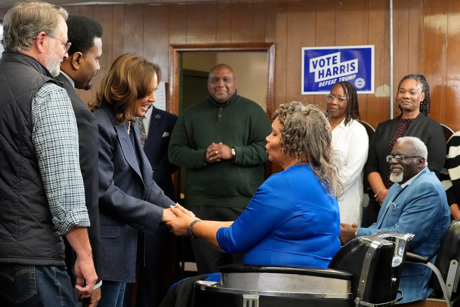 Democratic presidential nominee Vice President Kamala Harris, third left, greets Martha Roland, seated center right, and Roland Elam Sr., seated right, parents of Elam's barber shop owner Roland Elam Jr., second left, as Sen. Gary Peters, D-Mich., left, and others look on before participating in a roundtable discussion with local leaders at Elam's barber shop in Pontiac, Mich., Sunday, Nov. 3, 2024. (AP Photo/Jacquelyn Martin)