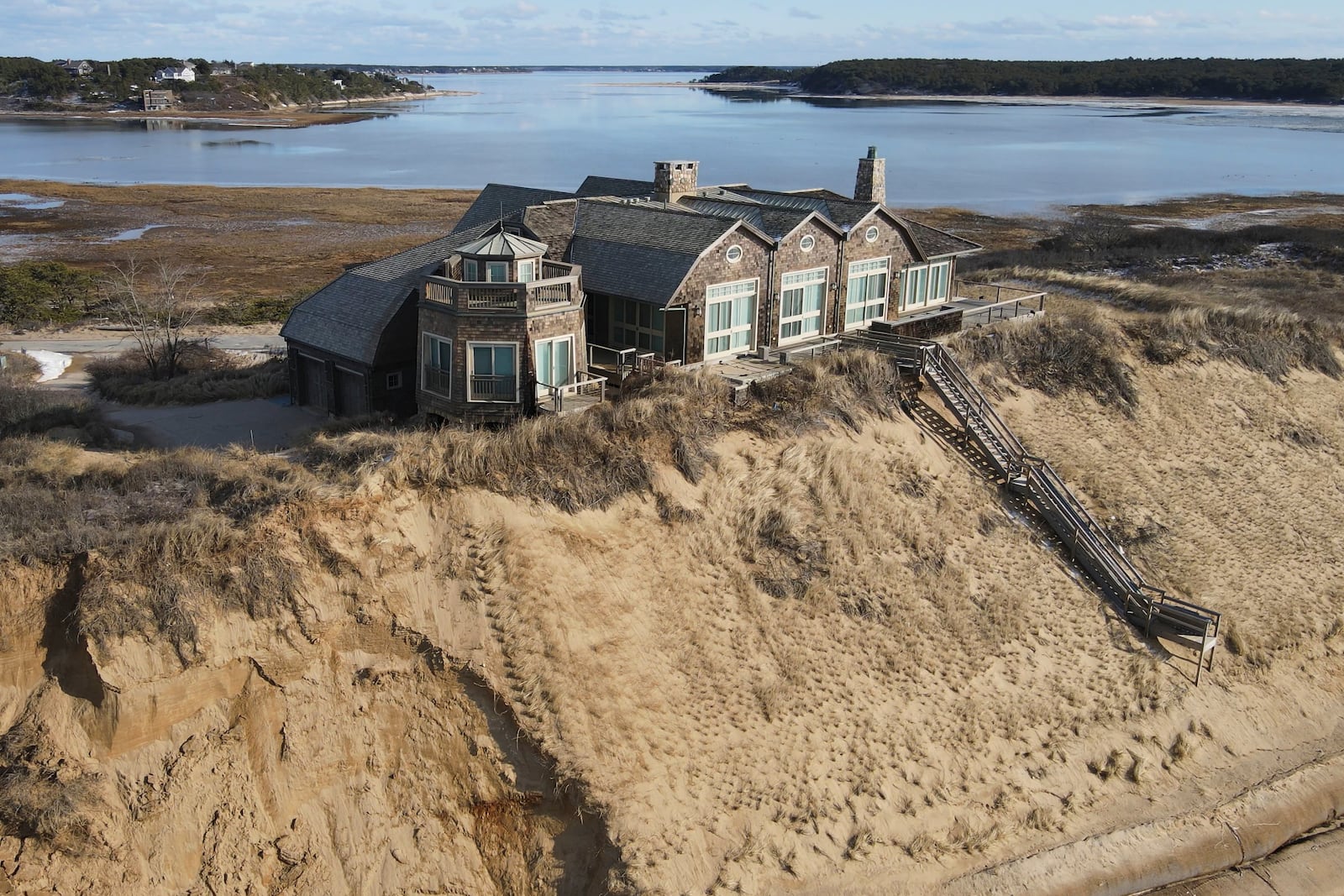 A home sits atop of a sandy bluff overlooking a beach in Wellfleet, Mass, Wednesday, Feb. 2, 2022. (AP Photo/Andre Muggiati)