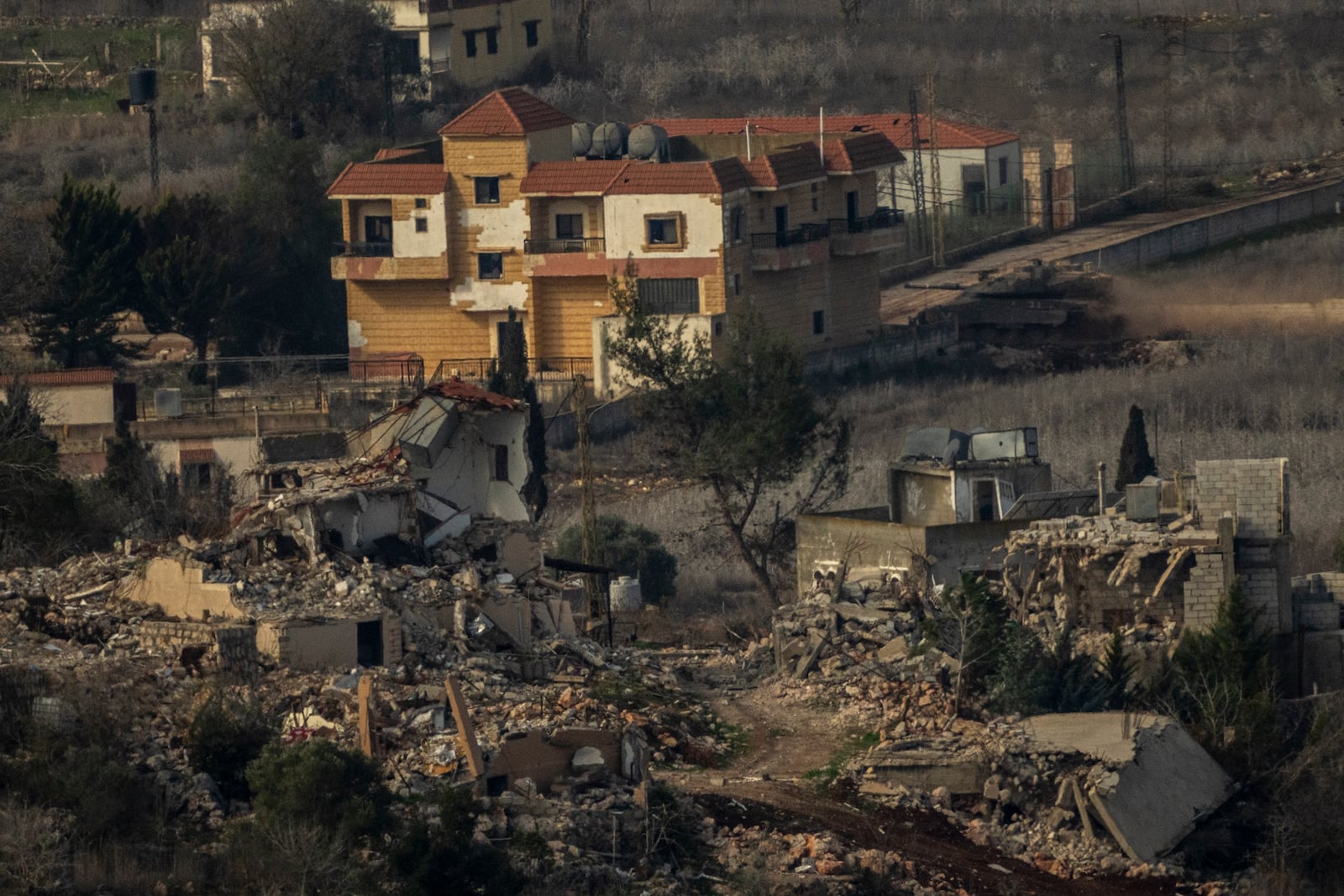 An Israeli tank maneuvers inside a village in southern Lebanon, as seen from northern Israel, Thursday, Jan. 23, 2025. (AP Photo/Ariel Schalit)