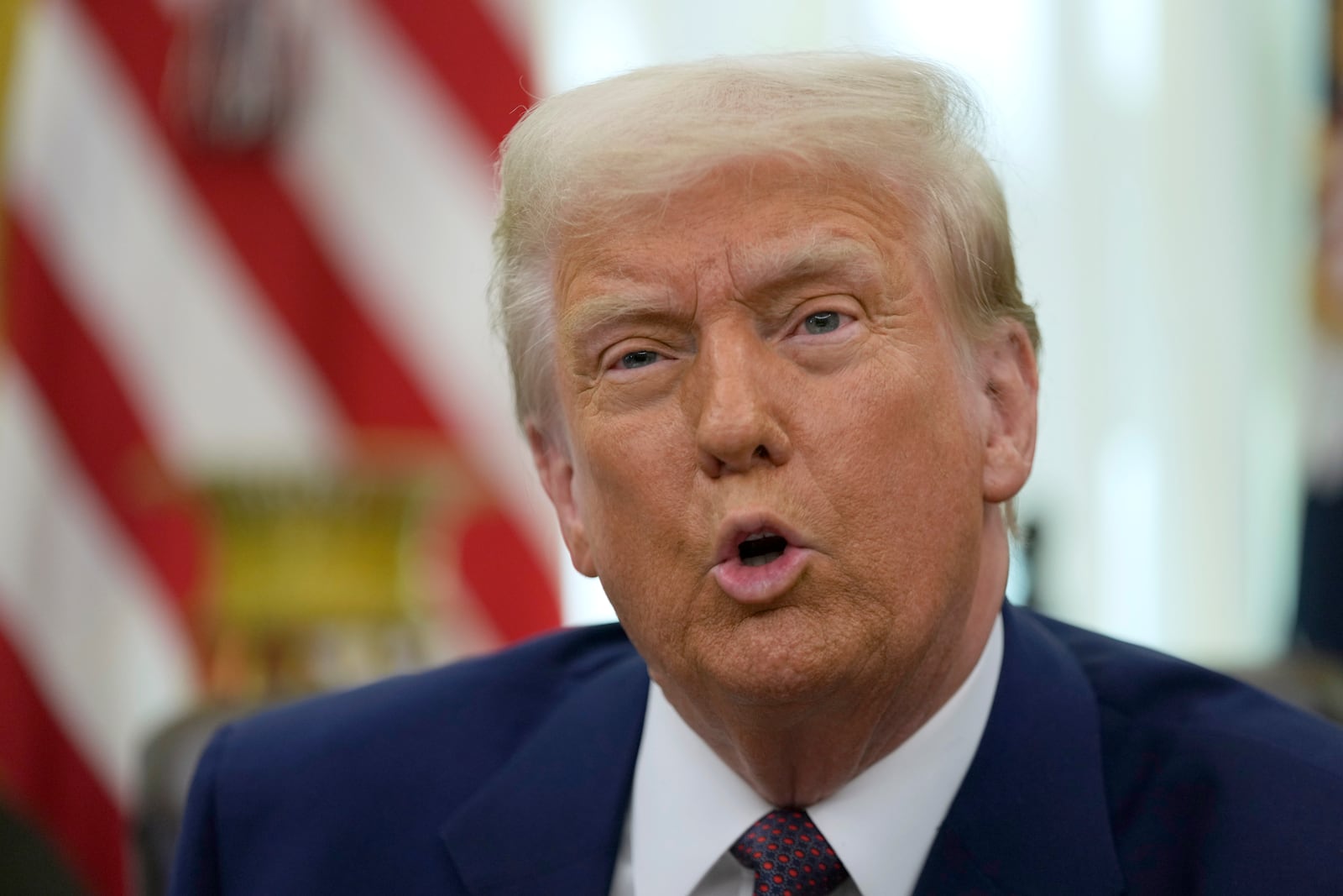 President Donald Trump speaks to reporters in the Oval Office of the White House, where he signed an executive order, Thursday, Feb. 13, 2025, in Washington. (AP Photo/Ben Curtis)