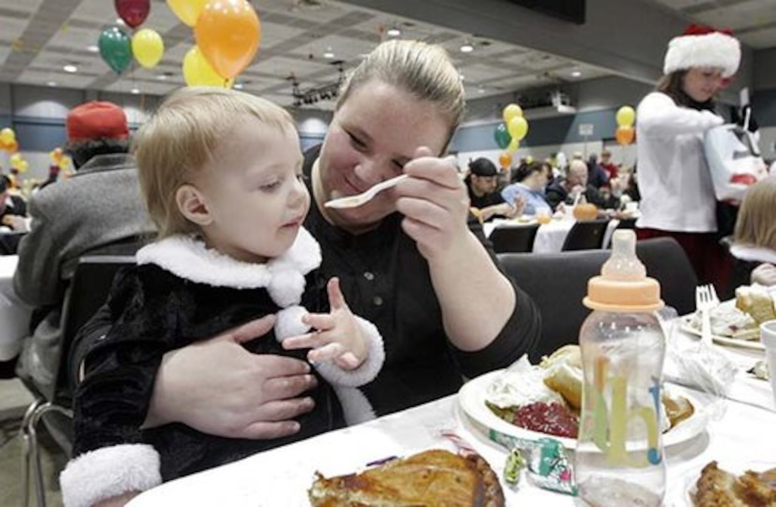 Tramara Fowler of Dayton feeds her 20-month-old daughter Sunshine at the annual Beerman Family Thanksgiving Day Dinner. Thousands of people attended the the annual Beerman Family Thanksgiving Day Dinner Thursday Nov. 27 at the Dayton Convention Center.