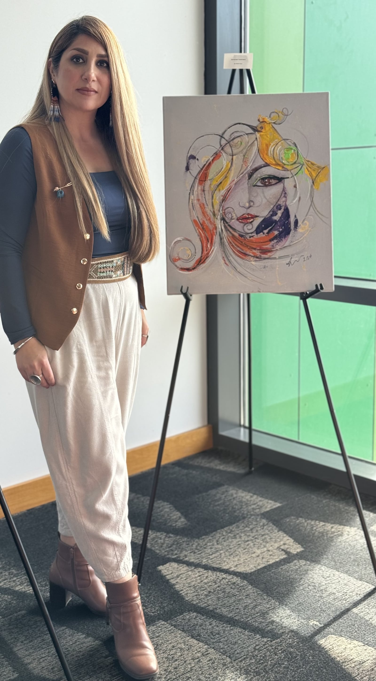 Samaneh Faramarzi, from Iran, is seen with one of her paintings at the downtown Dayton Metro Library. CONTRIBUTED