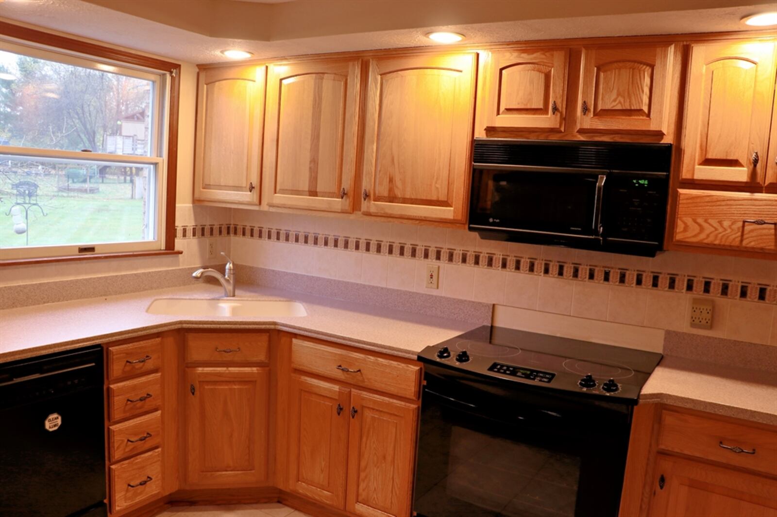 The kitchen has storage space for just about everything. Solid-surface counters wrap around three walls and complement the oak cabinetry. There is a double sink tucked into one corner and an appliance garage tucked into another.