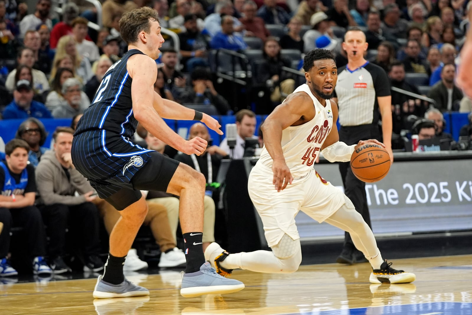 Cleveland Cavaliers guard Donovan Mitchell (45) drives past Orlando Magic forward Franz Wagner, left, during the second half of an NBA basketball game, Tuesday, Feb. 25, 2025, in Orlando, Fla. (AP Photo/John Raoux)