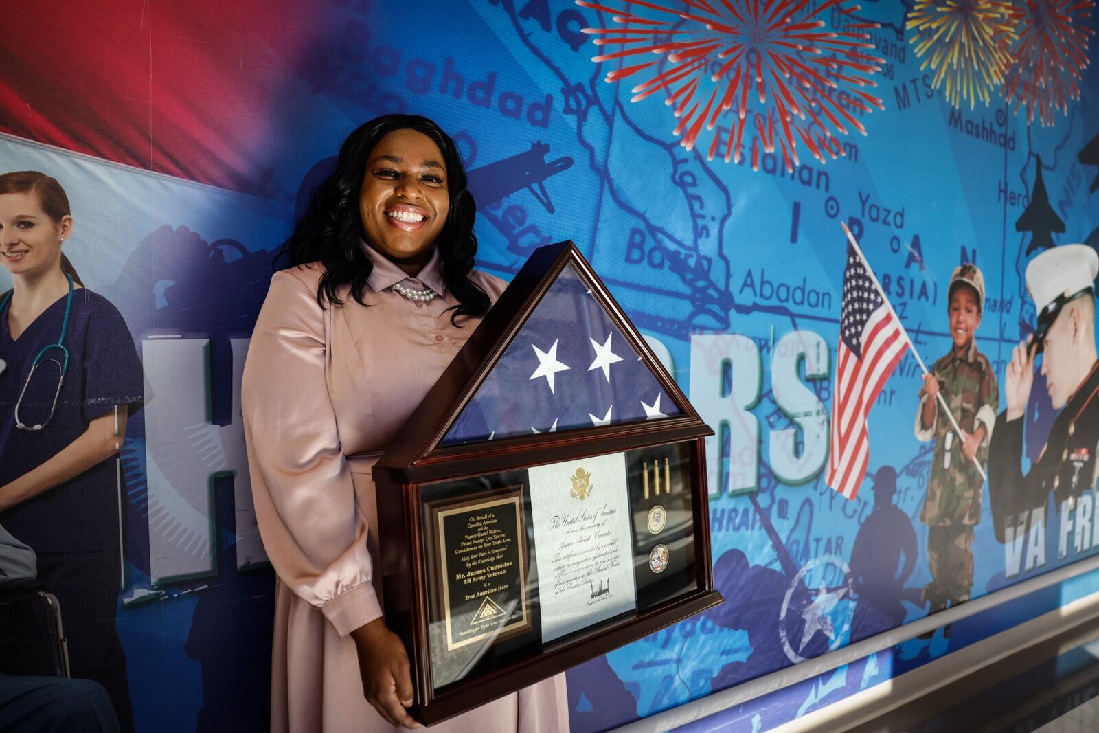 Dr. Carmela Daniels holds up a flag that was given to her at a veteran's funeral that she arranged. Daniels works at the Dayton VA in social services. JIM NOELKER/STAFF