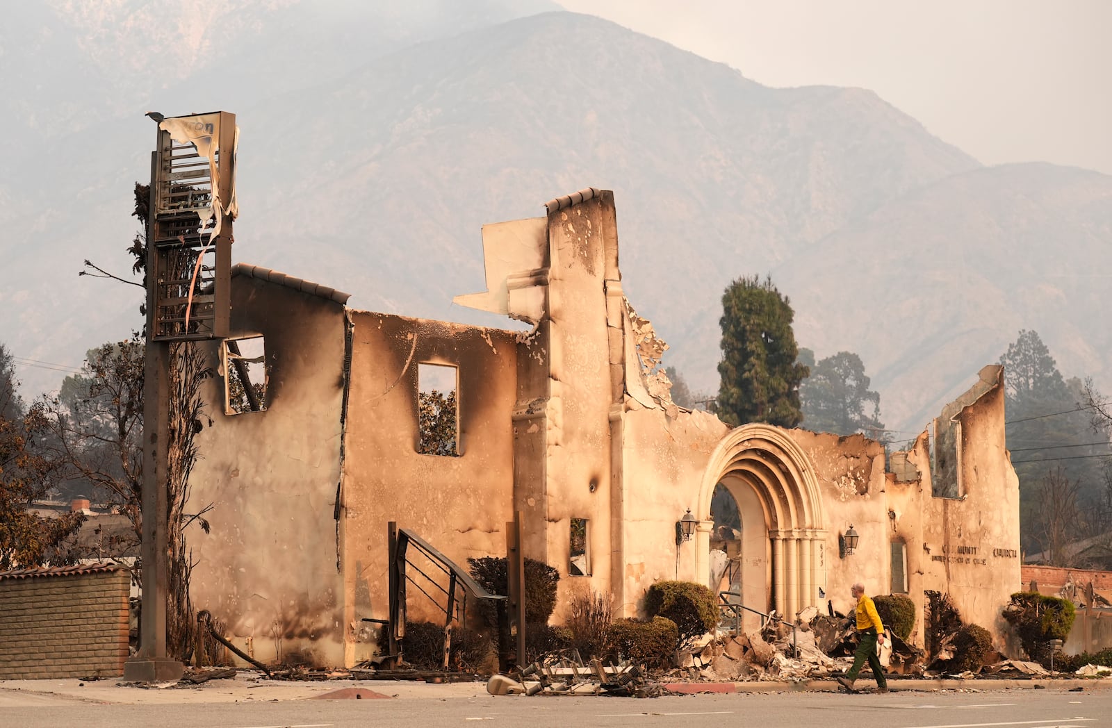 A man walks past the charred remains of the Altadena Community Church, Thursday, Jan. 9, 2025, in the Altadena section of Pasadena, Calif. (AP Photo/Chris Pizzello)