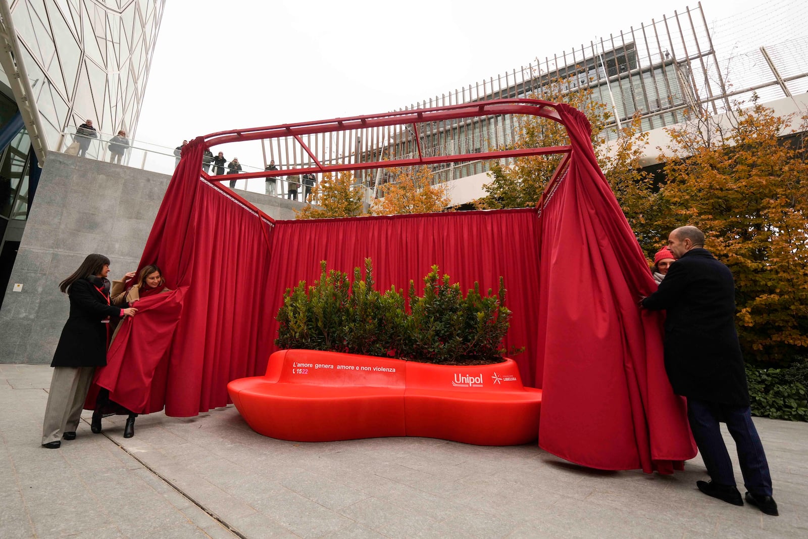 People participate in the unveiling of a red bench on the occasion of the International Day for the Elimination of Violence against Women, in Milan, Italy, Monday, Nov. 25, 2024. (AP Photo/Luca Bruno)