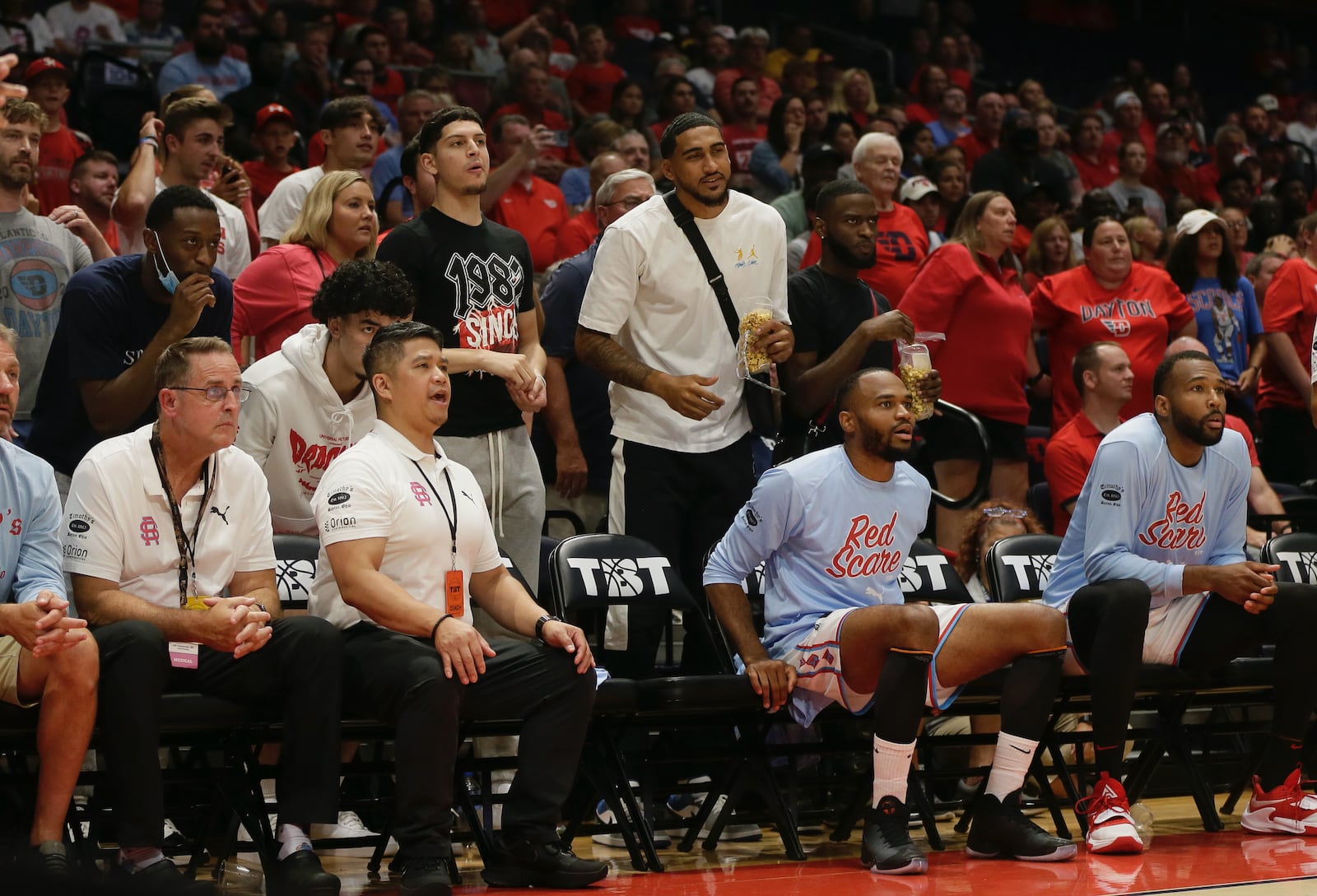 Obi Toppin and Jalen Crutcher and several current Dayton players watch from behind the bench during a game between the Red Scare and the Golden Eagles in The Basketball Tournament on Wednesday, July 27, 2022, at UD Arena. David Jablonski/Staff